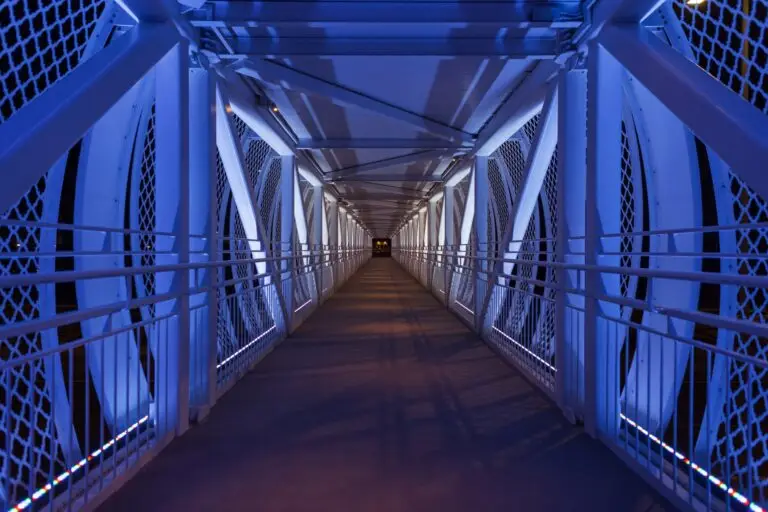 Beautiful foot bridge with blue colored lights at night. Path along the bridge. Transition